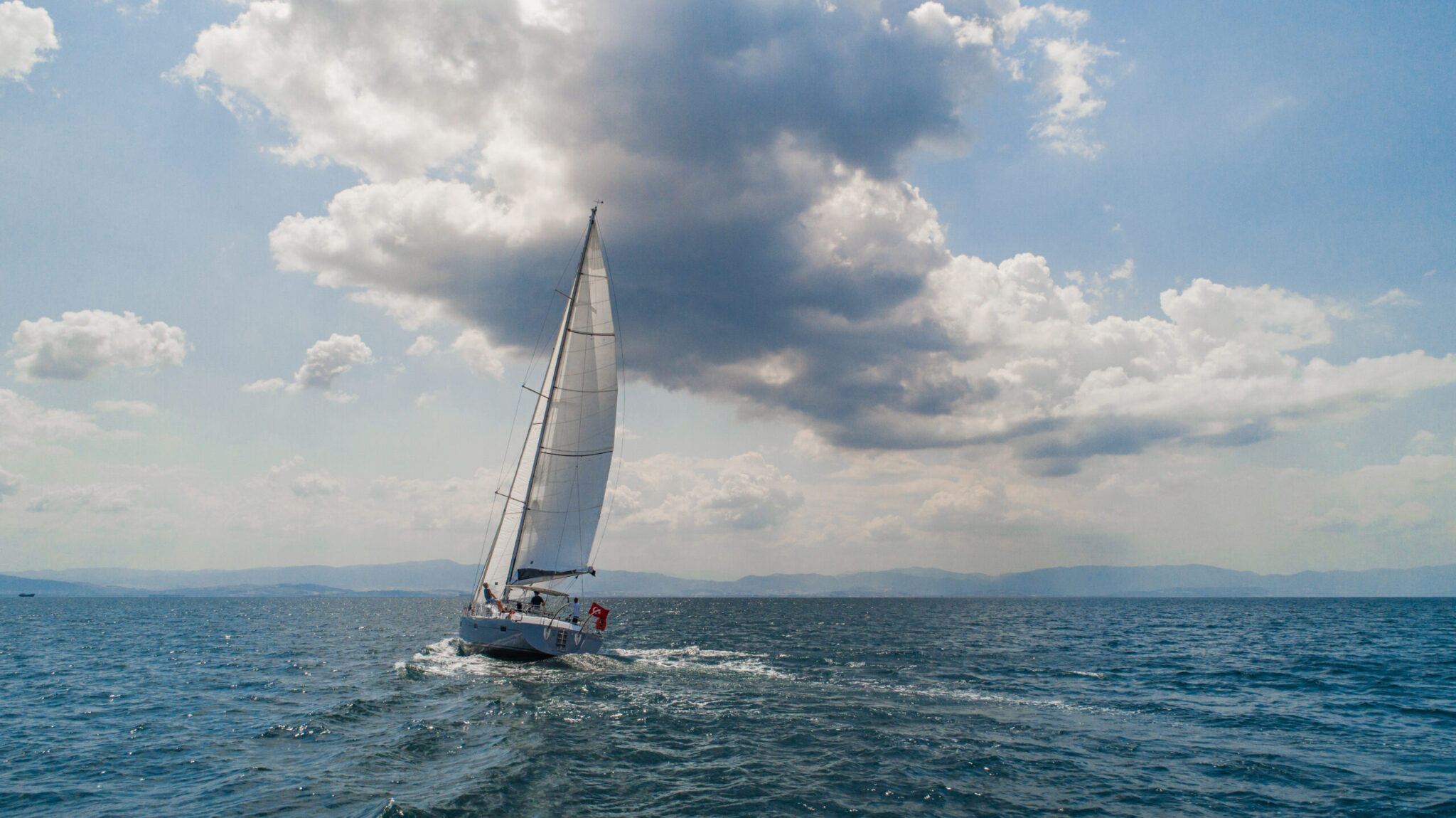 A Kraken yacht beating to windward under a towering cloud